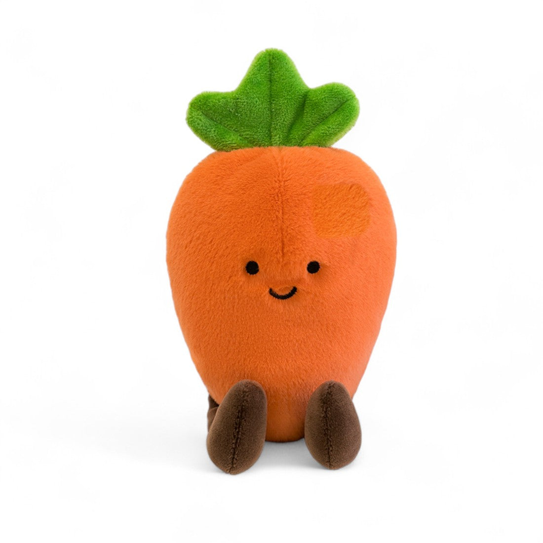 Kuscheltier Kawaii-Gemüse fröhliche Karotte, orange und grün, sitzend mit braunen Beinchen, Vorderansicht auf weißem Hintergrund.