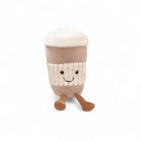 Kuscheltier in Kawaii-Optik in Form eines heißen Latte macchiato, mit hellbraunem Becher, weißem Schaum und lächelnden kleinen Beinen, auf weißem Hintergrund.