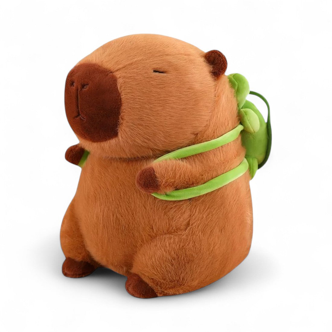 Kuscheltier Capybara, braun, mit grünem Schildkröten-Rucksack, sitzend auf weißem Hintergrund.