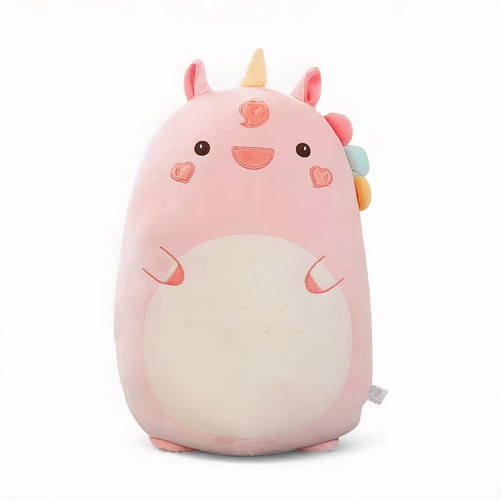 Großes Einhorn-Plüschkissen in Rosa, mit gelbem Horn, bunter Mähne, herzförmigen Wangen und großem cremefarbenem Bauch, auf einem Bett in einem hellen Zimmer.