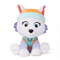 Everest-Kuscheltier von der Paw Patrol in Violett und Türkis, türkisfarbene Mütze mit orangefarbenem Rand, sanftes Lächeln, sitzend mit großen Ohren, auf weißem Hintergrund.