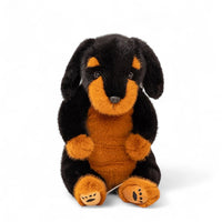 Rottweiler Kuscheltier schwarz und orange sitzend, schwarze Nase, naturgetreuer Blick, auf weißem Hintergrund.