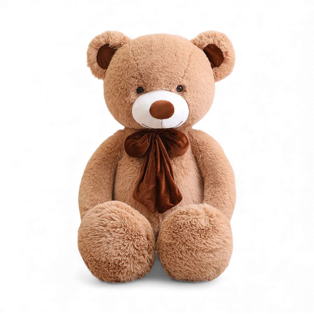 Teddybär aus Plüsch, hellbraun, mit großen Pfoten und einer großen braunen Samtschleife, sitzend auf einfarbigem Hintergrund.