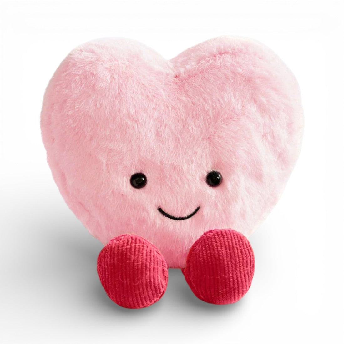 Ein weiches, flauschiges Kuscheltier in Herzform in Rosa, mit einem großen fröhlichen Lächeln, zwei runden glänzenden schwarzen Augen und zwei kleinen roten gestrickten Stoffpfötchen unten, auf einheitlich weißem Hintergrund